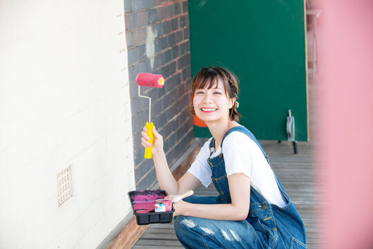 ペイントローラーを持って笑っている女性