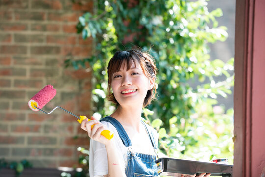 ペイントローラーを持って笑っている女性