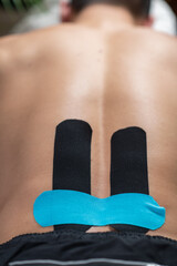 Elastic therapeutic kinesiology taping applied to the lower back for support and pain relief. - 791320389