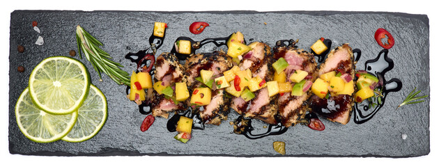 Sliced Organic grilled Tuna fillet covered with sesame seeds on black stone serving board