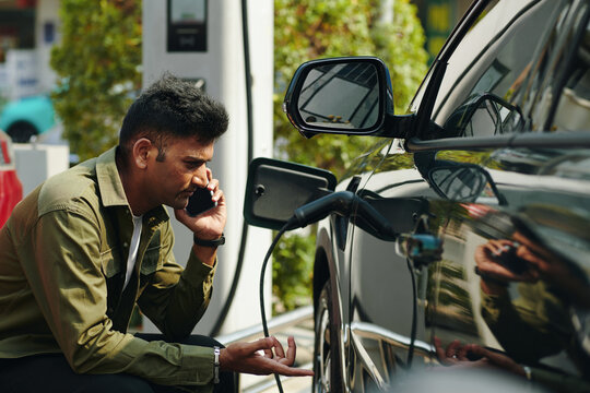 Frowning man calling service center as his electric car not charging