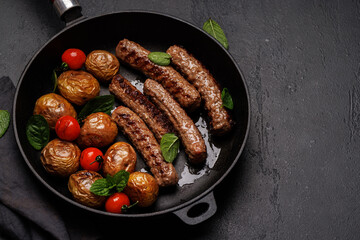 Delicious grilled sausages and potatoes in a sizzling frying pan