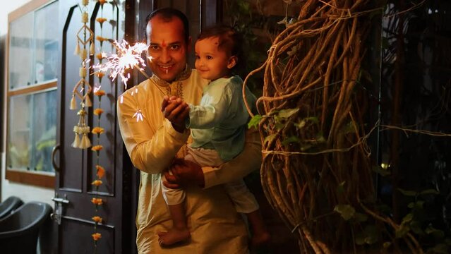 father and son celebrating diwali by burning sparkler at night from different angle