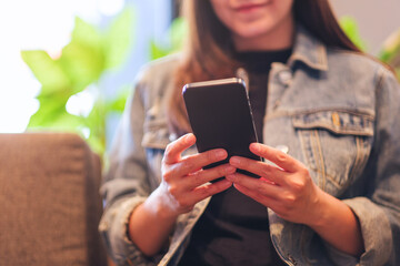 Closeup image of a young woman holding and using mobile phone in cafe - 791325313