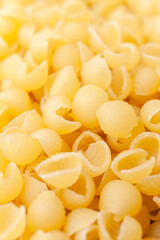 Uncooked, yellow, small shell shaped pasta background. Top view. Close-up