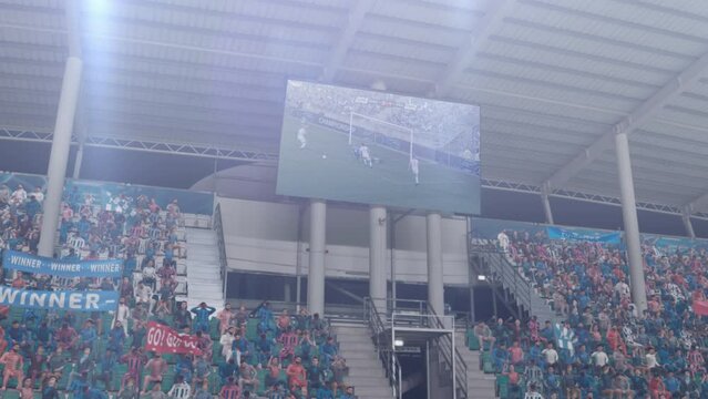 Soccer Fans Watch a High-Stakes European Football Championship Match on a Large Screen in a Packed Fan Zone at a Modern Stadium, Expressing Excitement and Team Spirit
