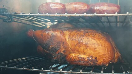 Whole chicken and sausages in a smoker outside 
