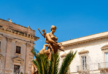 Syracuse, Sicily, Italy. Diana Fountain - Classic fountain with a statue of the goddess of the hunt Diana, created in 1907 by sculptor Giulio Moschetti. Sunny summer day - obrazy, fototapety, plakaty