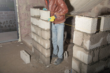 Worker builds a wall in the building site. - 791336199