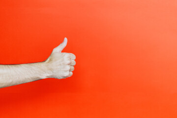 Person gesturing thumbs up against vivid red backdrop