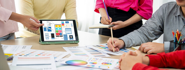 Cropped image of interior designer team chooses color from color swatches while tablet displayed UI...