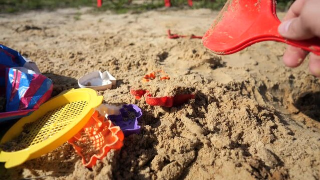 Little boy plays in the sandbox with his mother, a dump truck and a tractor