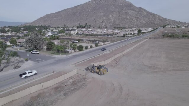 Drone tracks a backhoe loader navigating residential streets