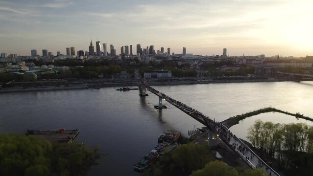 Slow aerial pullback at sunset above river and Warsaw Poland skyline