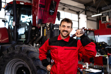 Professional serviceman with tools standing by tractor machine with hood opened.