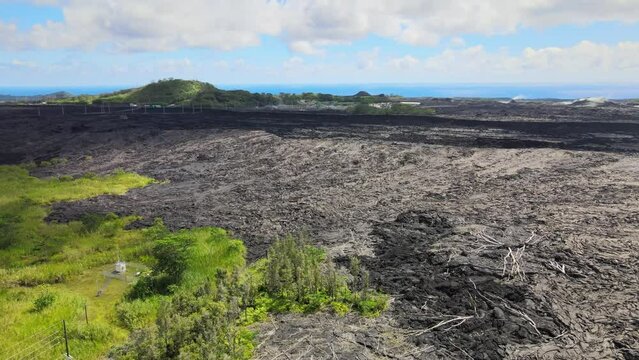 Drone pans, revealing expansive lava fields on Big Island, Hawaii, juxtaposed with unaffected areas from Leilani Estates eruption