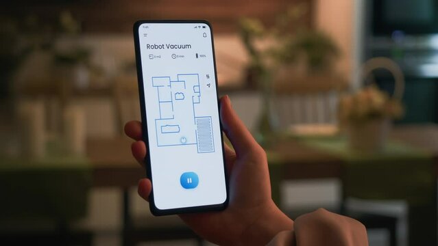 Turning on the robotic vacuum cleaner using a smartphone app. An autonomous robot vacuum cleans the apartment.
