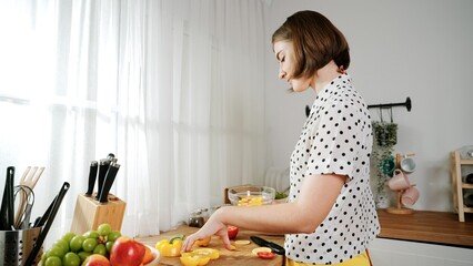 Caucasian mother put vegetable in bowl making a salad for breakfast while happy mom preparing fresh...