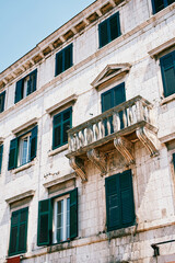 Old stone building with a balcony and green shutters on the windows. Kotor, Montenegro