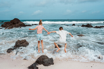 Siblings playing on beach, running, skipping rocks. Smilling girl and boy ion sandy beach with...