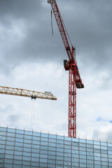 Red and yellow crane on a scaffolded construction site of a building - 791362336