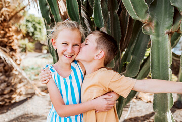 Portrait of siblings on summer vacation in holiday destination. Happy brother kissing sister on...