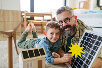 Father explaining renewable energy, solar power and teaching about sustainable lifestyle his young...