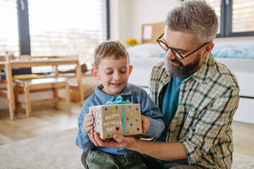 Dad get a handmade gift from little son, present wrapped in diy homemade wrapping paper. Happy...