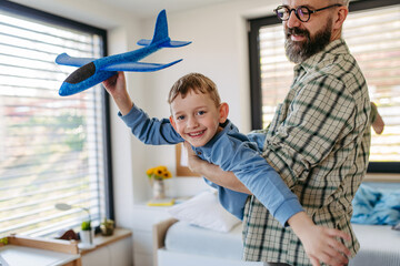 Playing with lightweight styrofoam planes. Playful father and son throwing and flying foam glider planes. Fathers day concept.