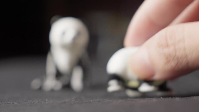 Hand Picking Up Miniature Figurine Toy Panda, Close Up With Blurred Background