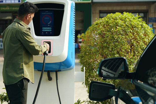 Driver taking plug from public point to charge his electric vehicle