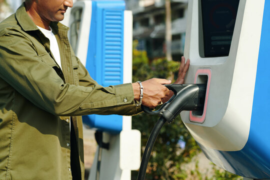 Cropped image of driver using public charging point