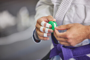 Brazilian jiu jitsu, hands and person with tape in gym for training, fitness or professional fighting sport. Injury, protection and martial arts athlete with gi, safety for fingers or workout in dojo