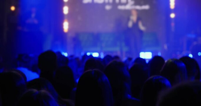 Shooting during a fashion show, a female fashion designer performs during a fashion show on stage in front of the audience. The speaker on women's happiness speaks in front of a large auditorium. 4k