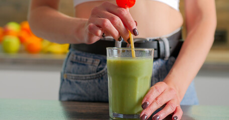 Woman drinks a green delicious smoothie at home