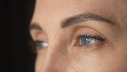 Thinking woman eyes and face on black background. Female looking into distance, eyebrows, eyelashes, skin issues macro view