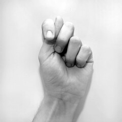 Letter T in American Sign Language (ASL) for deaf people, black and white photo of a hand