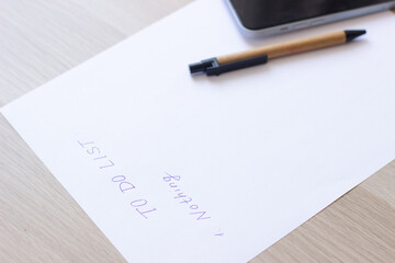 A white blank note or sheet of paper is on a wooden table background. To do list concept with no...