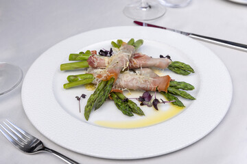 Rolled asparagus served  with cheese on a white plate - 791378193