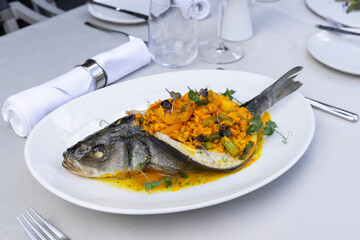 Sea bass served with risotto on a white plate - 791378599