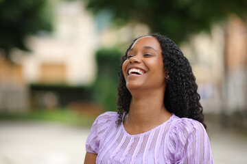 Happy black woman laughing alone in the street