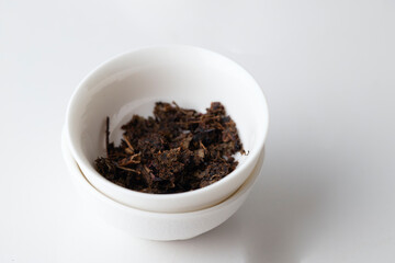 Dried tea leave s into the ceramic bowl on white background, tea time concept - 791389548