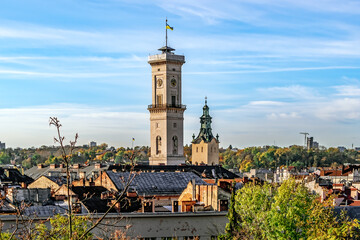 Lviv, Ukraine - November 2, 2023: Top view of the city panorama and the chapel of the Lviv Town Hall on an autumn morning. Close-up of city roofs against the backdrop of bare tree branches - Powered by Adobe