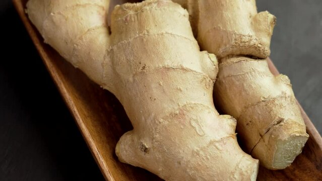 Aromatic fresh ginger root in a kitchen wooden bowl. Whole medicinal rhizome. Spicy asian ingredient. Zingiber officinale plant