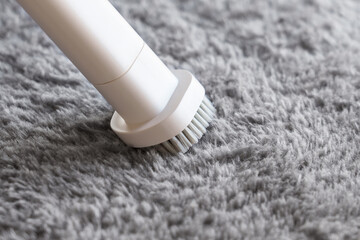 Cleaning grey carpet with white vacuum cleaner close up. Housework concept