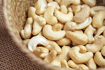 Raw organic cashew nuts in wicker rustic kitchen bowl close up