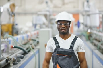 Professional Heavy Industry Engineer Worker Wearing Uniform, Glasses and Hard Hat in a Factory