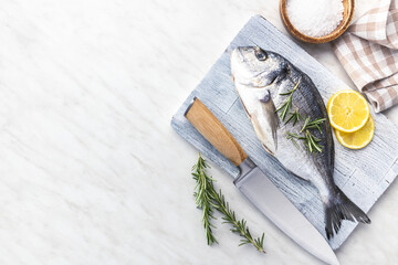 Fresh sea bream fish on cutting board on kitchen table. Top view. - 791402777