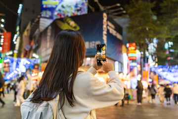 Fototapeta premium Young female tourist taking a photo of the Ximending shopping street landmark and popular attractions in Taipei, Taiwan