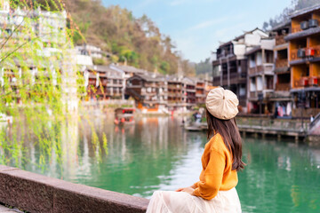 Young female tourist looking at the beautiful landscape of Feng Huang Ancient Town, The famous tourist destination at Hunan Province, China